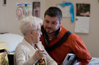 En la imagen aparece una señora, en su habitación, charlando con un profesional del Centro. 