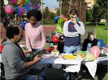 En la imagen aparece una fiesta en un jardín decorado con globos. Una de las personas que aparece tiene la cara pintada.