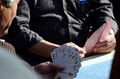 En la imagen aparecen unas manos de personas mayores jugando a un juego de mesa con una baraja de cartas.