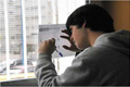 En la imagen aparece un chico joven cumplimenado un cuestionario. Está escribiendo apoyándose en el cristal de una ventana.