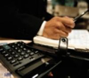 Imagen de una calculadora y una agenda personal sobre la que una persona se dispone a escribir.