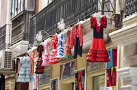 Fachada principal de una tienda en la que se exponen diversos objetos como una serie de trajes de baile flamenco.