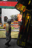 Es una fotografía de productos como frutas y aceite que se venden en un puesto de un mercado al aire libre.