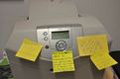 Impresora con varios pos-it, el central con el texto 'this is  a paperless office...'.