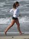 Una chica hace footing por la playa mientras escucha la radio.