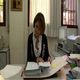 Fotografía en la que se ve una mujer sentada en una mesa consultando unos documentos.