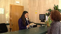 Imagen de una chica en su puesto de trabajo hablando por teléfono junto a otra mujer que la observa.