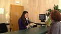 Imagen Luna en su puesto de trabajo hablando por teléfono junto a otra mujer que la observa.