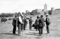 Foto antigua de un grupo de hombres que acuden a una feria de ganado cerca de la muralla de Ávila.