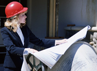 Una mujer con casco, mirando los planos en una obra en construcción.