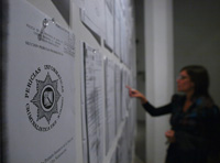 Mujer leyendo documentos en un tablón de anuncios.