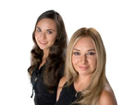 Dos chicas en primer plano, ambas de veintitantos años, una rubia de pelo largo y otra morena con el pelo también largo y algo ondulado posan sonrientes.