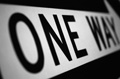 En la imagen se ve una flecha en blanco apuntando hacia la derecha y escrito en letras negras en el idioma ingles, one way, que significa dirección única.