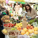 Mercado de puestos en la calle, donde se ve a gente comprando.