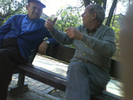 Dos personas mayores sentadas en un banco discutiendo.