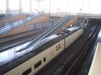Tren de alta velocidad circulando por las vías de una estación.