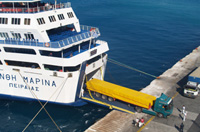 Camión amarillo desembarcando de la bodega de un ferry en el puerto.