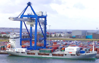 Transporte mercancías internacional. Barco en un puerto con una grúa grande de color azul cargando contenedores de mercancías.