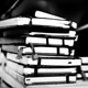 Varias libretas o libros en blanco y negro apiladas una encima de otra sin seguir un orden.