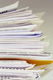 Muchos documentos, folios, carpetas apilados uno encima de otro.