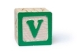 Un cubo, en una de sus caras aparece un recuadro verde y en su interior una letra, la v.