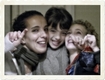 Una imagen de una mujer y dos niños sonriendo mirando al frente, hacen un gesto con la mano de aprobación.