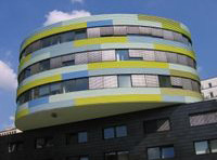 Es un edificio de oficinas de colores y circular.