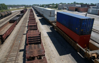 Aparece una estación de mercancías, trenes parados y contenedores.