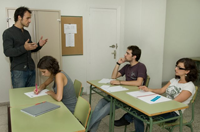 María Dolores, Ana, Alberto y Ahmed chanlando. Cuatro chicos, dos hombres y dos mujeres charlando en un aula, uno de los jóvenes está realizando una exposición.