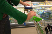 Mujer en un supermercado empujando un carrito de la compra.