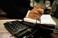 Persona delante de una mesa con calculadora,  documentos y agenda.