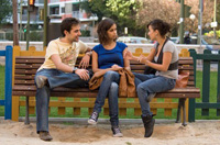 Ahmed, María Dolores y Ana. Dos mujeres y un hombre jóvenes sentados en un banco de un parque.