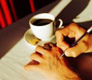 Dos manos, una escribiendo sobre la otra y una taza de café al lado.