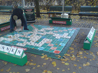 Scrabble gigante en un parque y un hombre colocando las fichas.