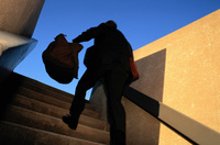 Ejecutivo con maletín en la mano subiendo unas escaleras a grandes saltos.