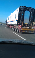 Camión de gran tonelaje circula por una autovía, con un vagón de tren como carga.