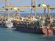 Barco de gran tonelaje descargando y a través de un puente grúa en un puerto marítimo.