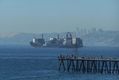 Buque portacontenedores cargado saliendo de la Bahía de Valparaíso, Chile. Se aprecia un pantalán con pescadores en primer plano.