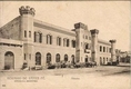 Antigua postal en tono sepia con una vista frontal de la antigua Aduana de Rosario (Argentina), edificio de dos plantas con torres similares a un castillo.