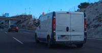 Furgoneta  blanca vista desde atrás circulando por autovía.