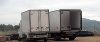 Camión Caja. Dos camiones blancos de mercancías perecederas aparcados, uno de ellos con la caja abierta.