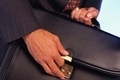 Persona sujetando una cartera con una mano y abriendo la cartera con la otra mano.