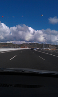 Geografía viaria. Aparece una autovía desde la perspectiva del conductor bajo un cielo azul con nubes blancas.