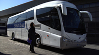 Aparece un autobús de viajeros blanco con una chica delante.