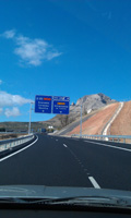 Aparece una autovía vista desde la perspectiva del conductor en la que al fondo se ven dos paneles azules indicativos.