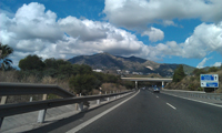 Aparece una autovía desde la perspectiva del conductor en la que circula delante un coche muy a lo lejos y a la derecha hay un panel de información.