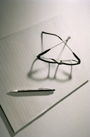 Derechos y deberes. Unas gafas y un bolígrafo se encuentran encima de un bloc de notas sin rellenar. Visto desde arriba.