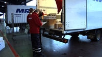 Responsable de transporte de mercancías. Hombre de unos 55 años de edad, vestido con chaqueta roja revisando un camión de descarga.