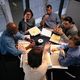 Varias personas reunidas y sentadas alrededor de una mesa.