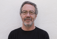 Hombre de mediana edad, con barba y gafas. Viste camiseta negra.